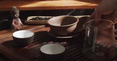  Atmosferik yakın çekim, Çin seremonisi için kuru çay hazırlayan kişinin görüntüsü. Yüzsüz usta kil çaydanlığı mayalanmış çayla dolduruyor yavaş çekimde. Elit teaware araçlar çanak çömlek