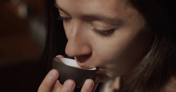 Közelkép egy fiatal nőről, aki egy csésze teát iszik 4 km-es lassított felvételen. Makró női arc élvezi aromás ital csukott szemmel természetes napfény. Pihenés boldogság élvezet