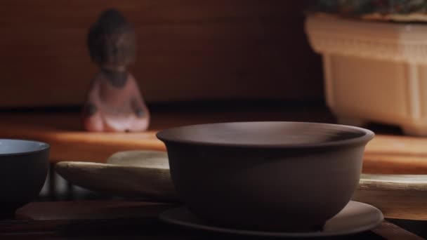 中国式を屋内で待っている木製のテーブルの上に立つ小さな粘土のティーカップの静止画 伝統的な東洋のアパートで日光の光線で空の特別な茶器のクラッチカップ — ストック動画
