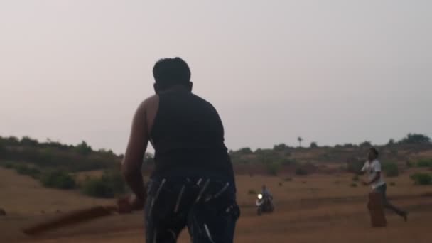 GOKARNA, INDIA-LUTY 23, 2020: Indianie grający w krykieta na świeżym powietrzu na wiejskim urządzeniu przenośnym. Ruch wideo z zawodników sportowych działa na suchej trawie krajobraz powolny ruch aktywny styl życia — Wideo stockowe