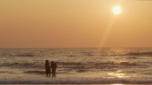 Ευτυχής οικογενειακό κολύμπι στο νερό του ωκεανού backlit από χρυσό ηλιοβασίλεμα φως αντίγραφο χώρο κειμένου. Άντρας γυναίκα παιδί μπάνιο μαζί σε εξωτερικούς χώρους τροπική παραλία αργή κίνηση. Καλοκαιρινές διακοπές ευτυχία μαζί — Αρχείο Βίντεο