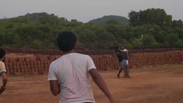 GOKARNA, INDIA-FEBRUARI 23, 2020: Aziatische mensen in casual kleding spelen cricket sport buiten op groene natuur achtergrond. Indiase mannen besteden vrije tijd met bal handheld apparaat slow motion — Stockvideo