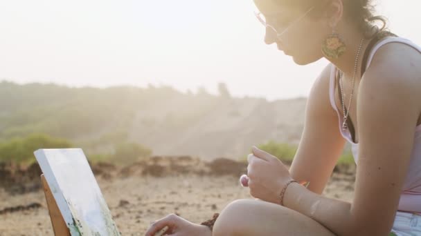 Vista laterale della donna pittura quadro su tela in estate luce dorata all'aperto. Close up pittore ragazza che lavora su opere d'arte sulla natura rallentatore. atmosfera umore felicità estate hobby concetto — Video Stock