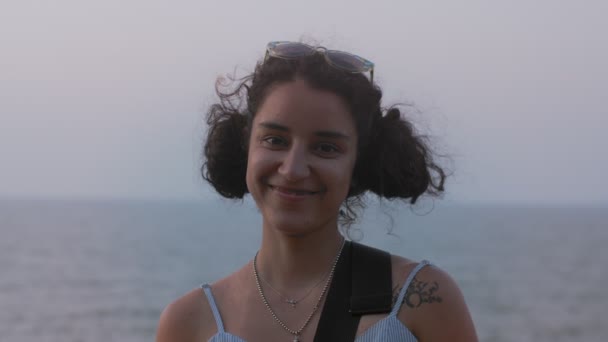 Retrato al aire libre de chica divertida sonriendo felizmente sobre fondo azul superficial cámara lenta. Joven mujer alegre posando en el estilo natural junto al mar sin maquillaje de moda. Personas reales estilo de vida headshot — Vídeos de Stock