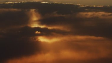 Güneşin altın bulutlu gökyüzünde batışının manzarası. Hızlı uçan bulutlarla renkli turuncu gün batımı. Etkileyici doğanın atmosferik video çekimi. Ekoloji çevre koruma kavramı