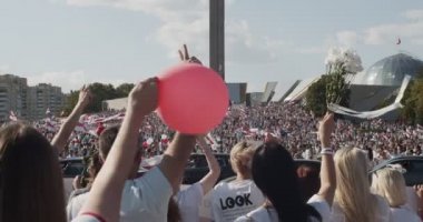 MINSK, BELARUS - 16 AĞUSTOS 2020: insanlar anıtın yakınındaki barışçıl protestolara katılıyor. Çiçekleri ve bayrakları olan insanlar diktatörlüğe karşı gösteri yapıyorlar. Belaruslular Şiddeti Durdurun