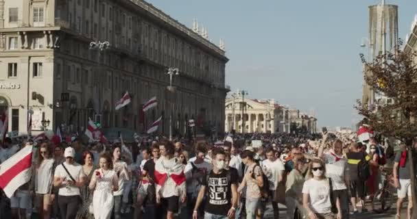 Беларусь - 16 августа 2020 года: Мирные протестующие с плакатами и флагами движутся по улицам города. Белорусы приняли участие в демонстрациях в Беларуси против диктатуры Александра Лукашенко — стоковое видео