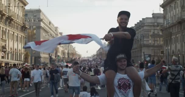 MINSK, BELARUS - 16 sierpnia 2020: Młodzi mężczyźni machający biało-czerwono-białą narodową flagą historyczną Białorusi na proteście. Ludzie protestują przeciwko dyktaturze Aleksandra Łukaszenki. Nowe uczciwe wybory — Wideo stockowe