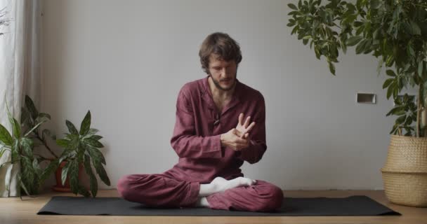 Pemijat depan thai masseur di kelas master menunjukkan cara memijat jari tangan. Orang yang duduk berkaki silang pada tikar yoga peregangan otot dalam ruangan gerak lambat. Relaksasi perawatan tubuh kesehatan — Stok Video