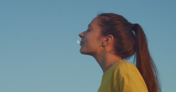 Ευτυχισμένη νεαρή γυναίκα που φιλάει πανσέληνο σε φόντο μπλε ουρανού. Πλευρική άποψη του κοριτσιού με τα μαλλιά σε αλογοουρά χαμογελώντας στη γη δορυφορική αντίγραφο κείμενο χώρο αργή κίνηση. Φορητή συσκευή πυροβολήθηκε. Εραστές της αστρονομίας — Αρχείο Βίντεο