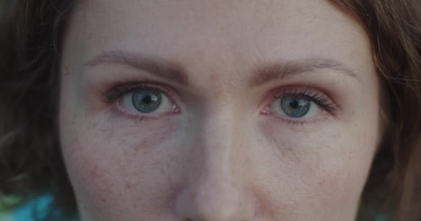 Extra zblízka ženské modré oči s malým make-upem řasenka otevření zpomalení detailní oříznutí. Makro portrét bílé ženy s pihami vypadá vážně. Péče o pleť zdravé oči zrak koncept — Stock video