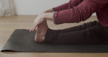 Yogi 'nin bacaklarını paschimottanasana' da yavaş çekimde esnetirkenki detaylı görüntüsü. Güneşli odada tek başına hatha yogası yapan bir adamın makro görüntüsü. Vücut sağlığı esnekliği