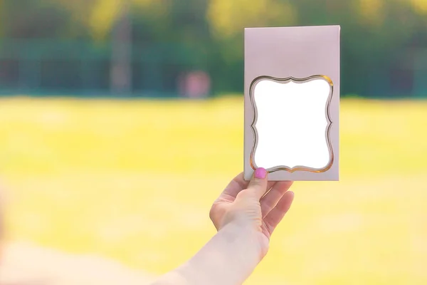 woman holding pink card with mirror at outdoor