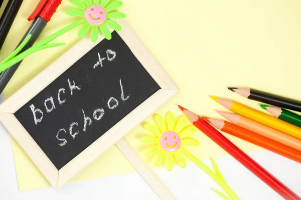 回到学校 Conceptl 五颜六色的毛毡笔和 Pancils 的特写 黄色和绿色雏菊和小黑板在黄色背景 图库照片
