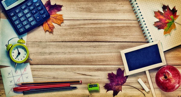 回到学校 Conceptl 计算器 黑板笔 一根粉笔 红苹果和枫叶上的木质背景 图库图片