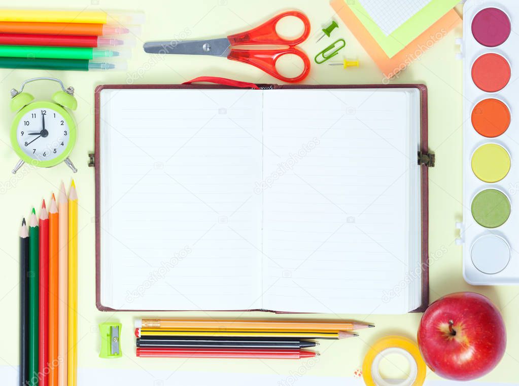 Back to School Conceptl: Empty Notebook, Colorful Pens, Pencils, Felt Pens, Red Apple, Sissors, Palette of Paint on the Yellow Background