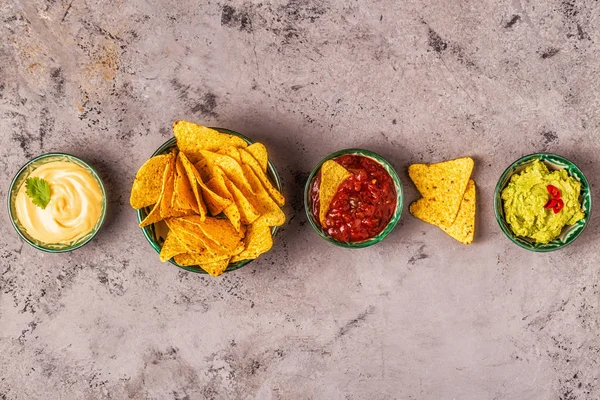 Mexican food background: guacamole, salsa, cheesy sauces with na