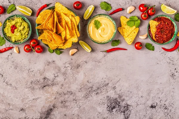 Mexican food background: guacamole, salsa, cheesy sauces with na