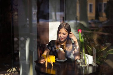 Kız kahve içer ve cep telefonu video izler