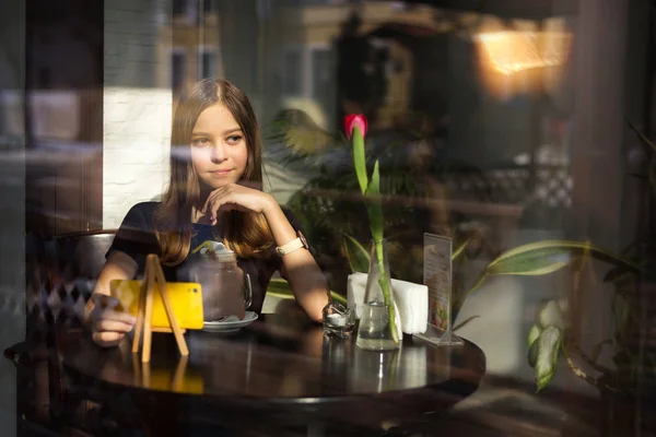 girl drinks coffee and watches video on mobile phone