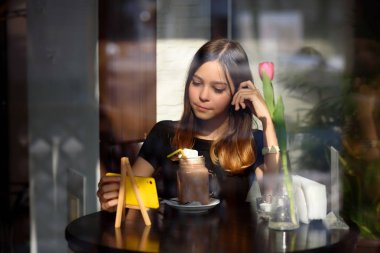 Kız kahve içer ve cep telefonu video izler