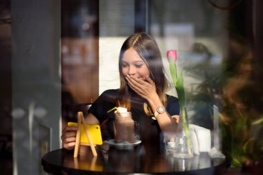 Kız kahve içer ve cep telefonu video izler