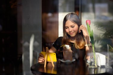 Kız kahve içer ve cep telefonu video izler