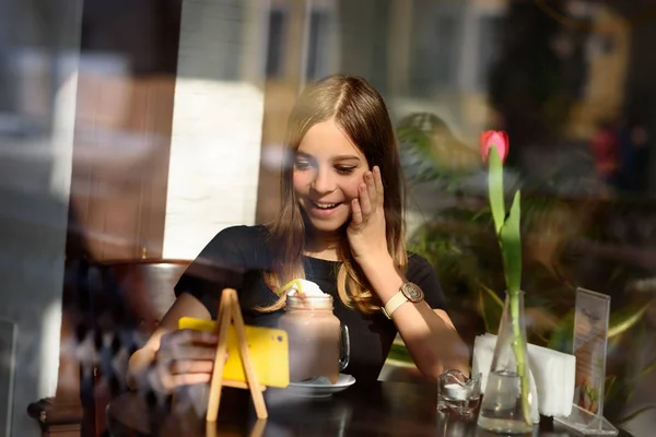 girl drinks coffee and watches video on mobile phone