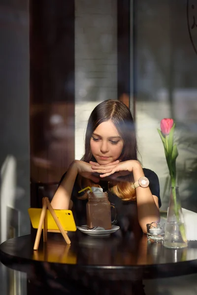 girl drinks coffee and watches video on mobile phone