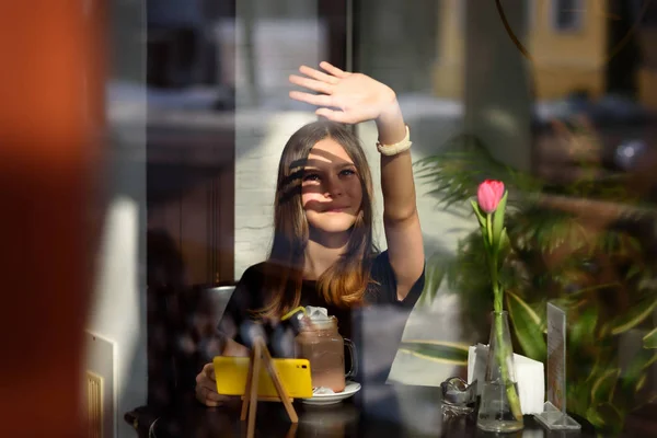 girl drinks coffee and watches video on mobile phone