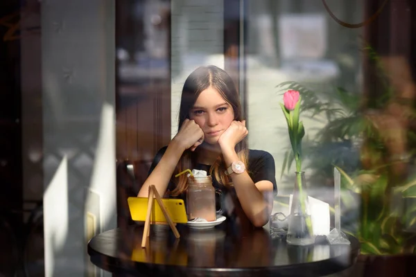 girl drinks coffee and watches video on mobile phone