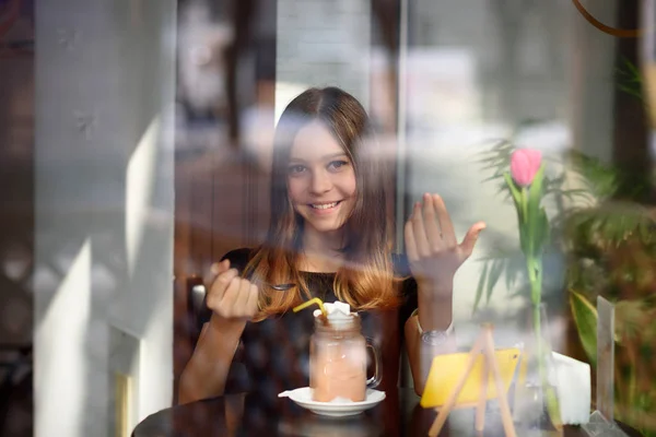 girl drinks coffee and watches video on mobile phone