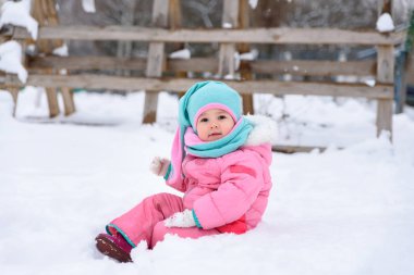 küçük kız pembe Tulum içinde karlı bir kış parkta yürüyor