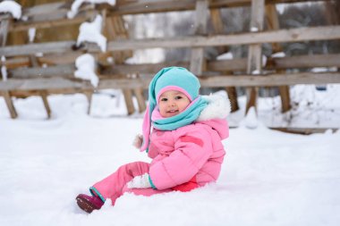 küçük kız pembe Tulum içinde karlı bir kış parkta yürüyor