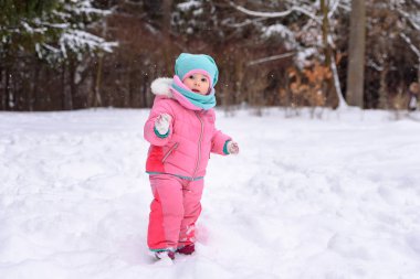 küçük kız pembe Tulum içinde karlı bir kış parkta yürüyor