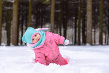 küçük kız pembe Tulum içinde karlı bir kış parkta yürüyor