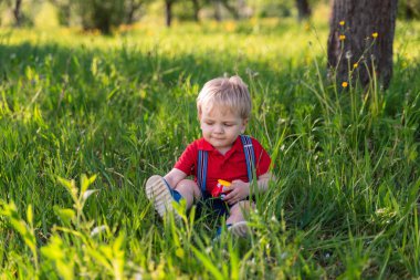 Küçük çocuk çimen renkli oyuncakla oynuyor.
