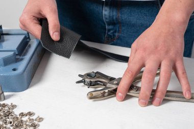 Ustanın elleri delgiyle düğmeye delik açar.