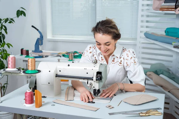 atölye çalışanı dikiş makinesine deri eşyaların küçük parçalarını karalıyor