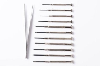 Küçük parçalar ve cımbızlar düz beyaz arkaplanda yatar