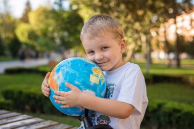 Küçük çocuk dünyayı kucaklıyor ve gülümsüyor.