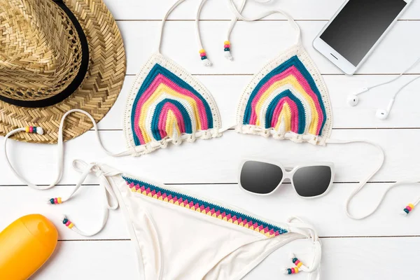 Beyaz ahşap zemin üzerinde plaj aksesuarları ile mayo