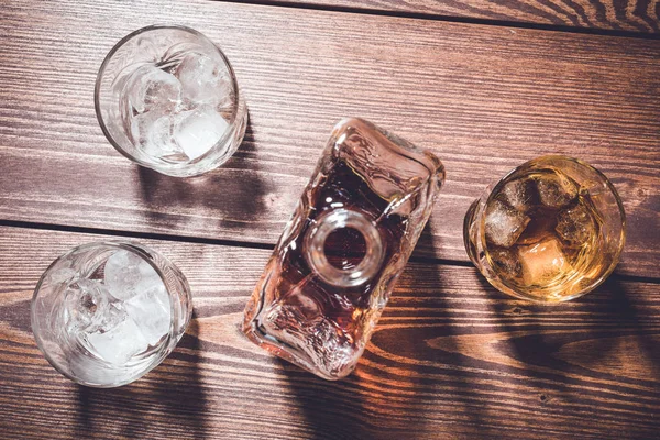 Whiskey bottle and whiskey glasses with ice cubes. Top view