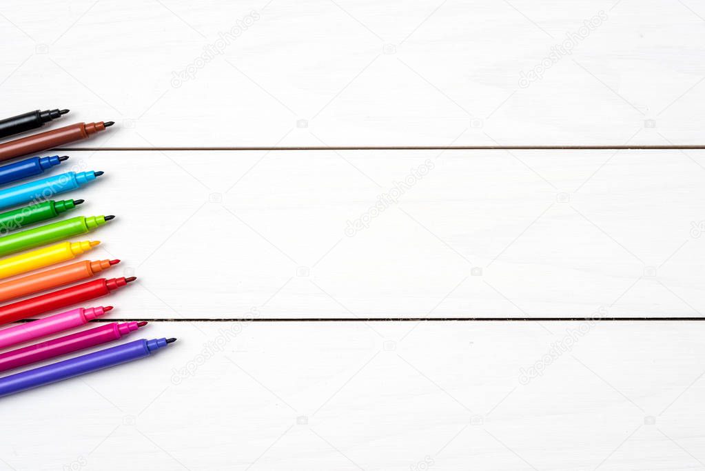 Close up shot of colorful markers on white wooden table