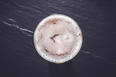 Koyu gri taş zemin üzerine bira cam. Üstten görünüm