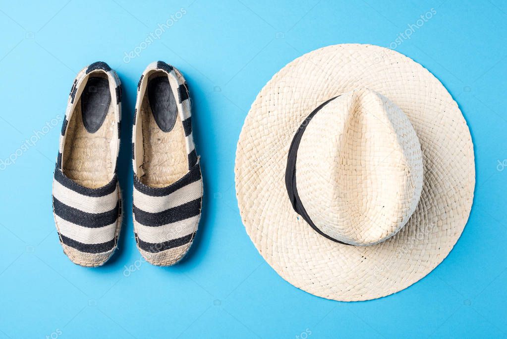 Straw hat and espadrilles on blue background