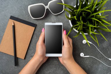 Gri taş masa üzerinde bir akıllı telefon kullanan kadın. Üstten görünüm