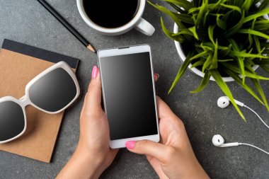 Gri taş masa üzerinde bir akıllı telefon kullanan kadın. Üstten görünüm