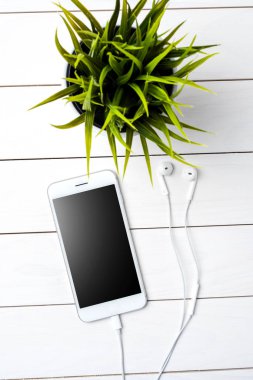 Beyaz ahşap zemin üzerinde kulaklık ile modern smartphone
