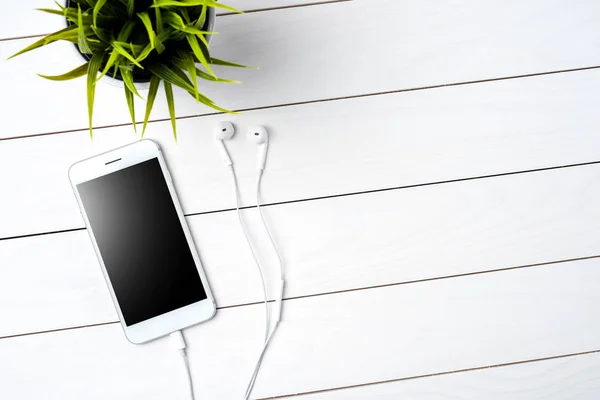 现代智能手机与耳机的白色木质背景 — 图库照片